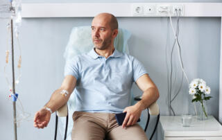Adult man sitting in chair with IV drip during treatment session in clinic