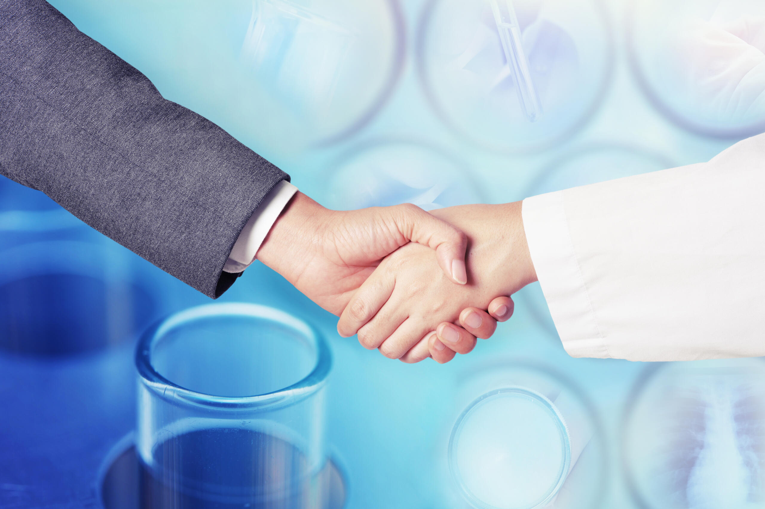 business man hand shake with doctor, background consisting of test tubes and other scientific instruments.